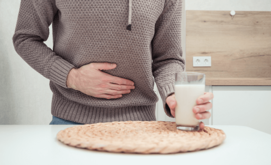 An image of a man holding his tummy and a glass of milk