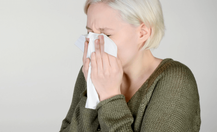 A woman wiping her nose with a large tissue